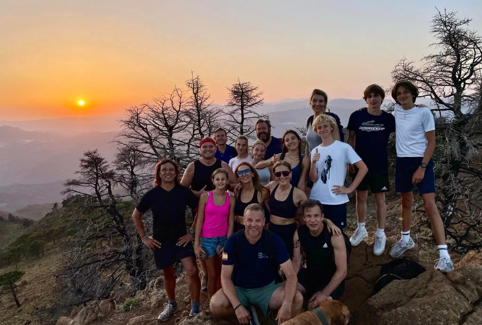 people-on-a-trek-smiling-on-top-of-mountain-in-the-sunset